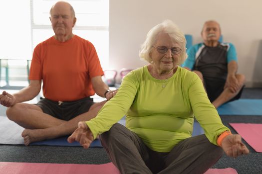 Front view of senior people doing yoga in position yoga in fitness studio