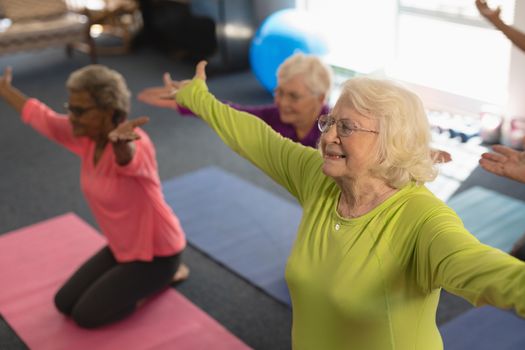 Happy senior people exercising in yoga position in fitness studio