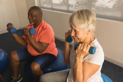 Side view of active senior people exercising with dumbbells at home