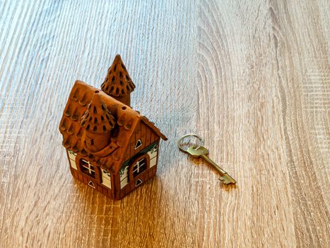 Model of a house and golden key On Wooden Table. Real estate agency, mortgage loan, lottery, buying property.Home loan and investment concept. Copy space