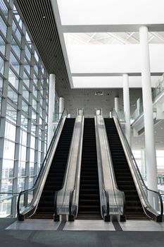 Front view of three modern escalators in a office lobby against inside buildings in background