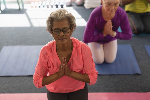 Front view of senior woman doing yoga in fitness studio