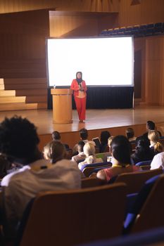 Front view of mixed race businesswoman giving speech in front of audience in the auditorium