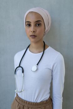 Portrait of beautiful young mixed-race female doctor standing with stethoscope in hospital. She is looking at camera