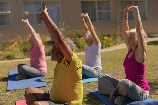 Side view of active senior people performing yoga on yoga mat in the park