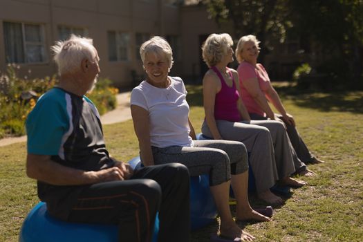 Side view of active senior people interacting with each other and sitting on exercice ball  the park