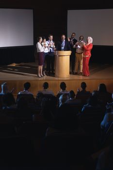 Front view of mixed race business colleagues clapping hand for there colleague  for the success in the auditorium stage in front of the audience