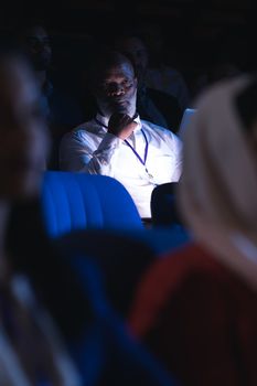 Low angle view of old African-American businessman looking and thinking while sitting in the auditorium