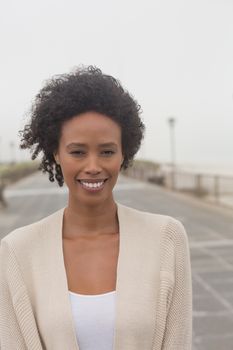 Portrait of happy young African American woman looking at camera on promenade. She is smiling