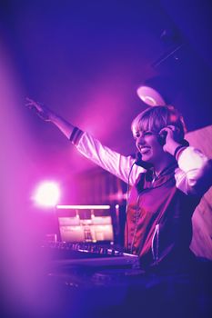 Pretty female dj waving her hand while playing music in bar
