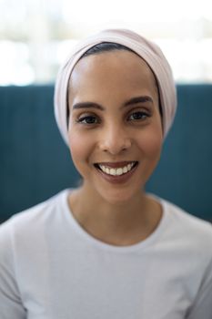 Portrait of beautiful young mixed-race female executive standing in the lobby at office. She is looking and smiling at camera