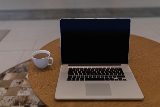 Laptop and cup of tea on a table in the lobby at office