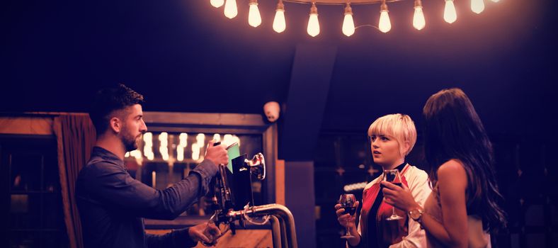 Bartender interacting with beautiful women at counter in bar