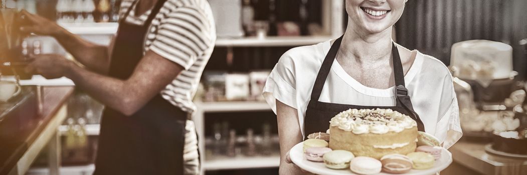 Portrait of waitress holding dessert on cake stand in cafe