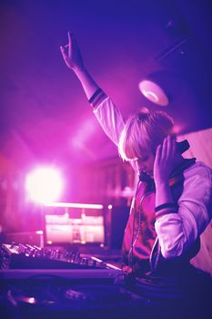 Pretty female dj waving her hand while playing music in bar