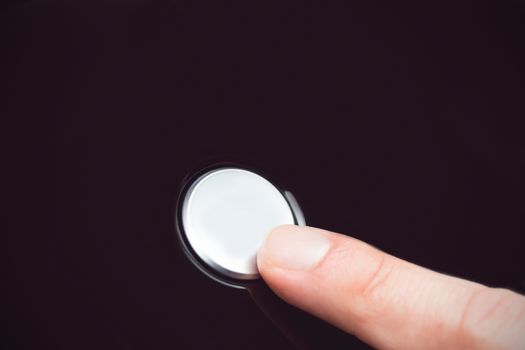 White finger pressing a small white button 
