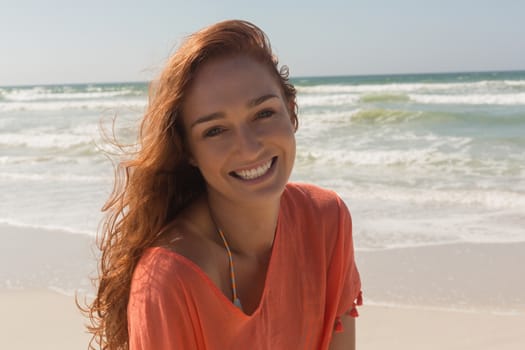 Front view of beautiful happy young Caucasian woman looking at camera on the beach. She is smiling