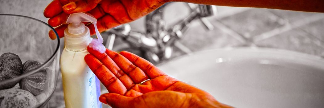 Cropped hands using soap dispenser by sink in bathroom at home