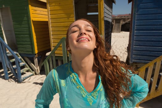 Front view of happy gorgeous young woman looking at camera standing on the beach. She is smiling