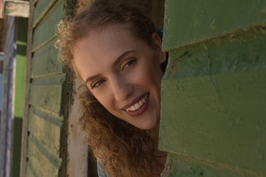 Close-up of happy gorgeous young Caucasian woman looking away from beach hut. She is smiling