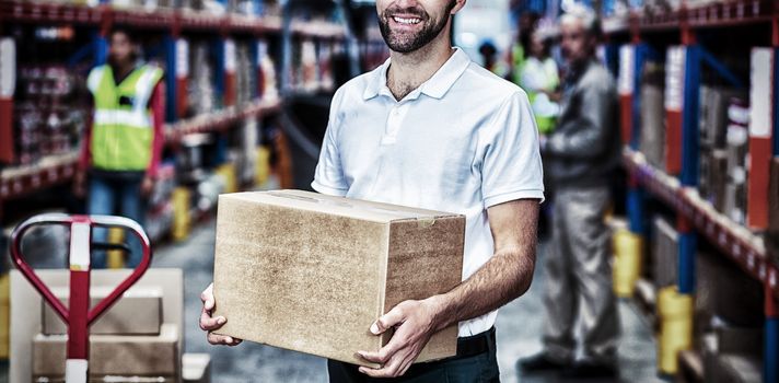 Portrait of worker is holding cardboard boxes and smiling to the camera in a warehouse