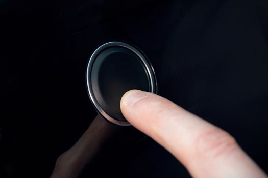 White index finger pressing a small black button 