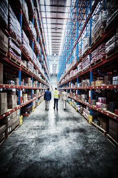 Rear view of warehouse team discussing while walking in warehouse
