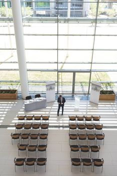 High angle view of well dressed businessman practising speech in empty conference room 