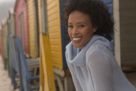 Portrait of happy young African American woman standing at beach hut. She is smiling and lookig at camera