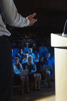Rear view of businessman giving presentation in front of audience in auditorium