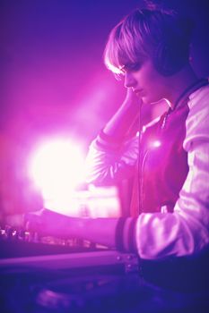 Female dj listening to headphones while playing music in bar