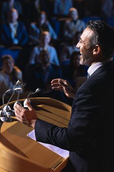 Side view of Caucasian businessman standing and giving presentation in the auditorium 