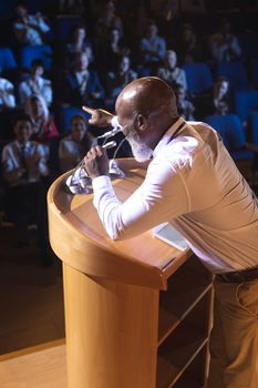 High angle view of old African-American businessman standing  and holding speaker while asking question to the audience 