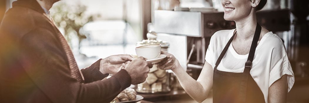 Waitress serving a cup of coffee to customer in cafe