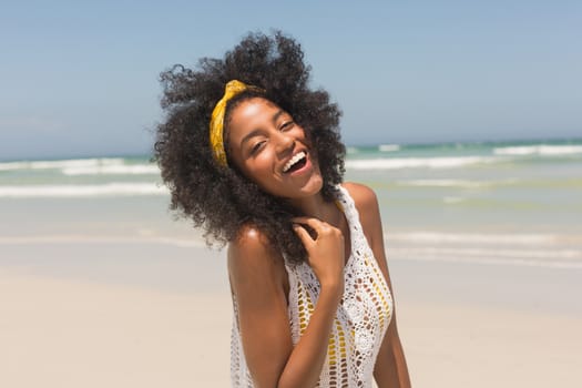 Portrait of happy young African American woman looking at camera standing on the beach. She is smiling