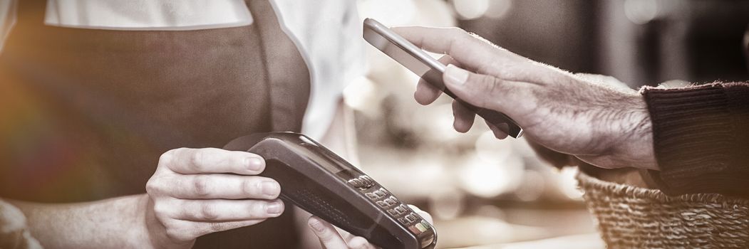 Customer paying bill through smartphone using NFC technology in cafe, Close-up