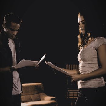 Actors reading their scripts on stage in theatre