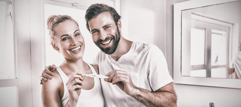 Portrait of happy couple checking pregnancy test in bathroom