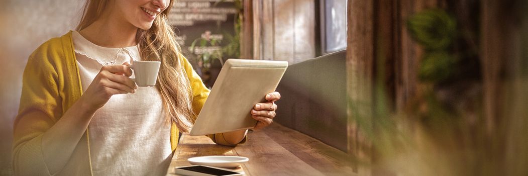 Smiling woman drinking coffee and using tablet in the cafe