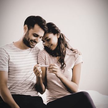 Joyful couple finding out results of a pregnancy test in the bedroom at home