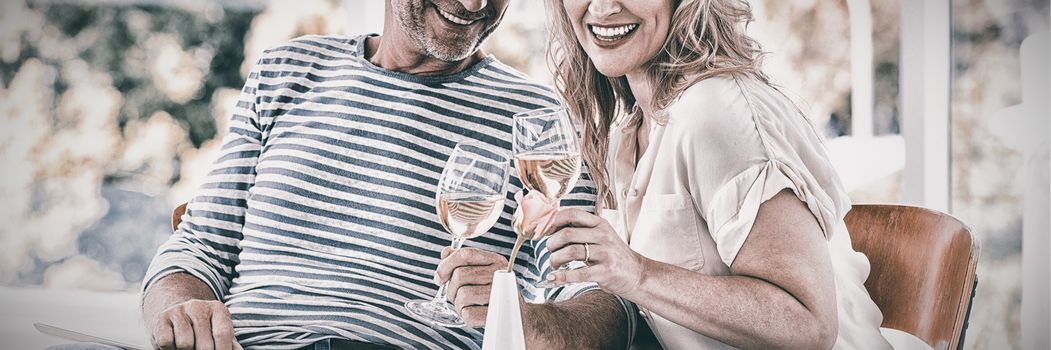 Portrait of smiling mature couple holding wine glasses at restaurant