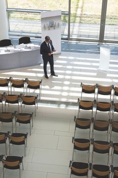 High angle view of mixed race businessman practising speech in empty conference room in modern office building