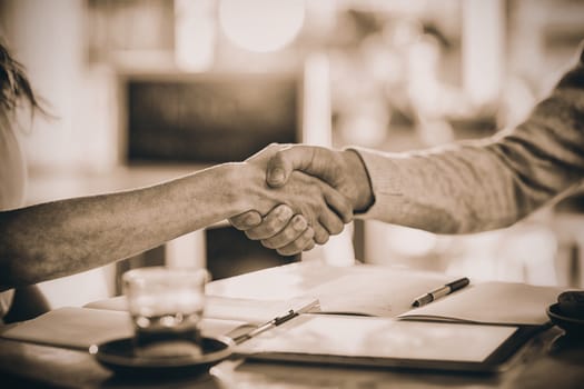 Friends shaking hands in cafe, Close-up