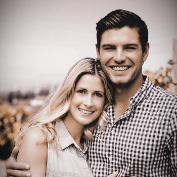 Portrait of happy couple embracing at vineyard during sunny day