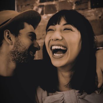 Young man whispering in cheerful woman ear at cafe