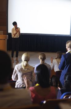 Front view of beautiful Asian businesswoman thanking the audience while finished her presentation in auditorium