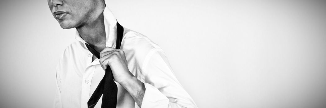 Confident transgender female holding tie while standing against white background