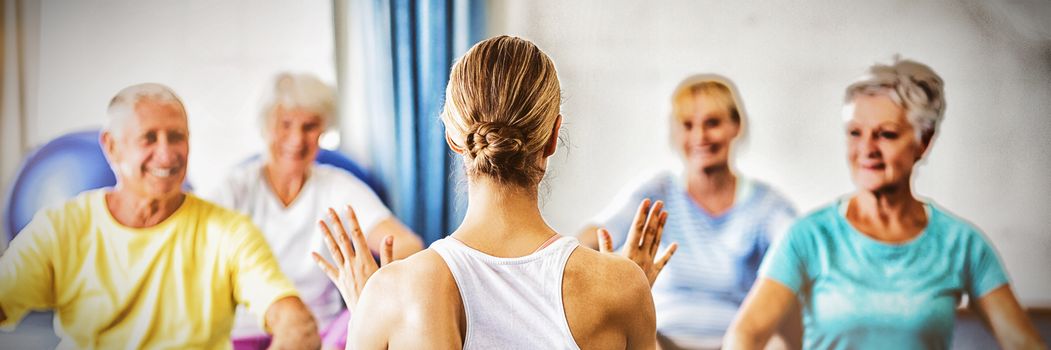 Instructor performing yoga with seniors during sports class