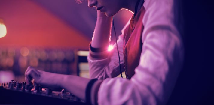 Female dj listening to headphones while playing music in bar