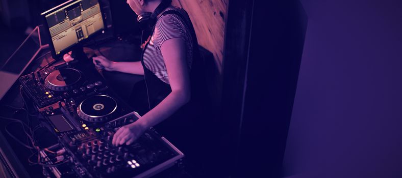 Female dj mixing music on mixing console in bar